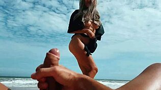 Blondine wichst Schwanz mit Füßen am öffentlichen Nacktbadestrand