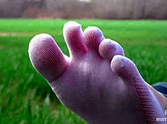 Goddess feet in cute white socks spread on spring grass field