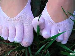 Goddess feet in cute white socks spread on spring grass field