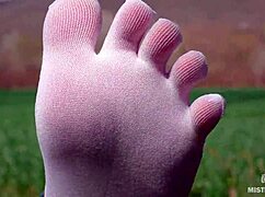 Goddess feet in cute white socks spread on spring grass field