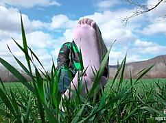 Goddess feet in cute white socks spread on spring grass field