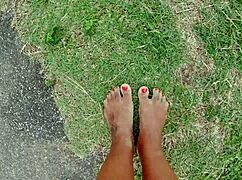 African pornstar walks barefoot on beach and street, dirtying feet.