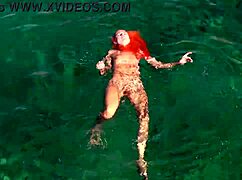 A girl relaxes in blue water while naked outdoors.