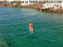 A girl relaxes in blue water while naked outdoors.