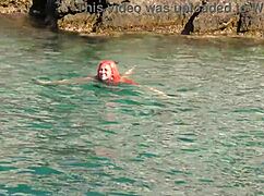 A girl relaxes in blue water while naked outdoors.