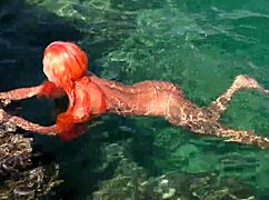 A girl relaxes in blue water while naked outdoors.