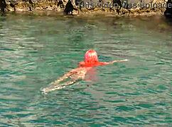 A girl relaxes in blue water while naked outdoors.