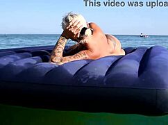 Beautiful blonde girl enjoys nude beach with big boobs and dolphin tattoo in public nudist outdoor setting