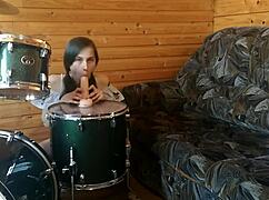 A petite brunette teen masturbates intensely with big dildo atop her drumset